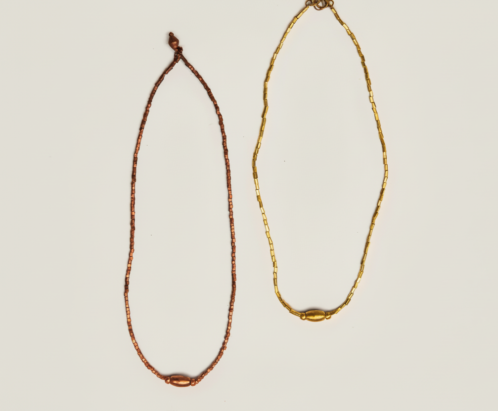 Two necklaces, one brown and one gold, on a white background