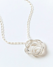 Silver knot pendant necklace on a white background