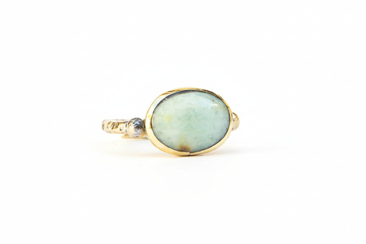 Gold ring with a green gemstone on a white background