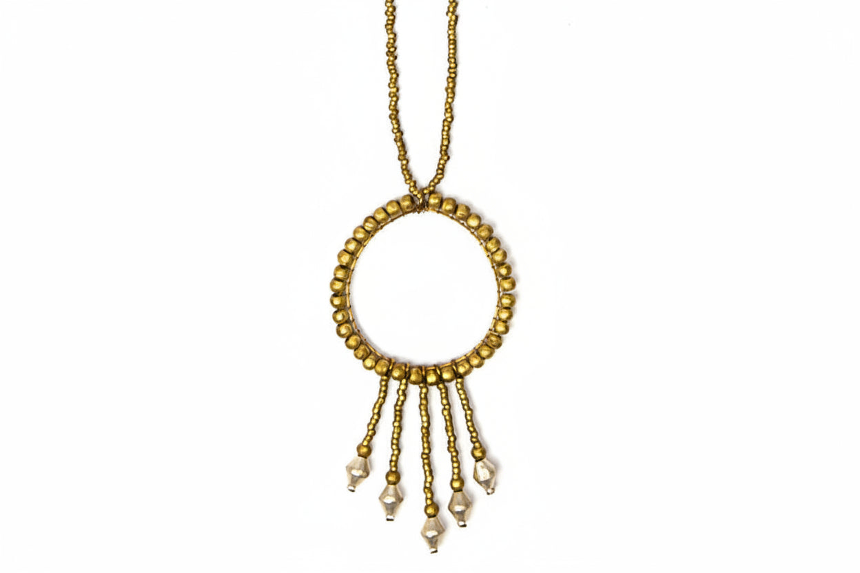 Gold necklace with circular pendant and dangling beads on a white background