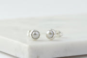 Pair of silver earrings with pearl-like stones on a marble surface