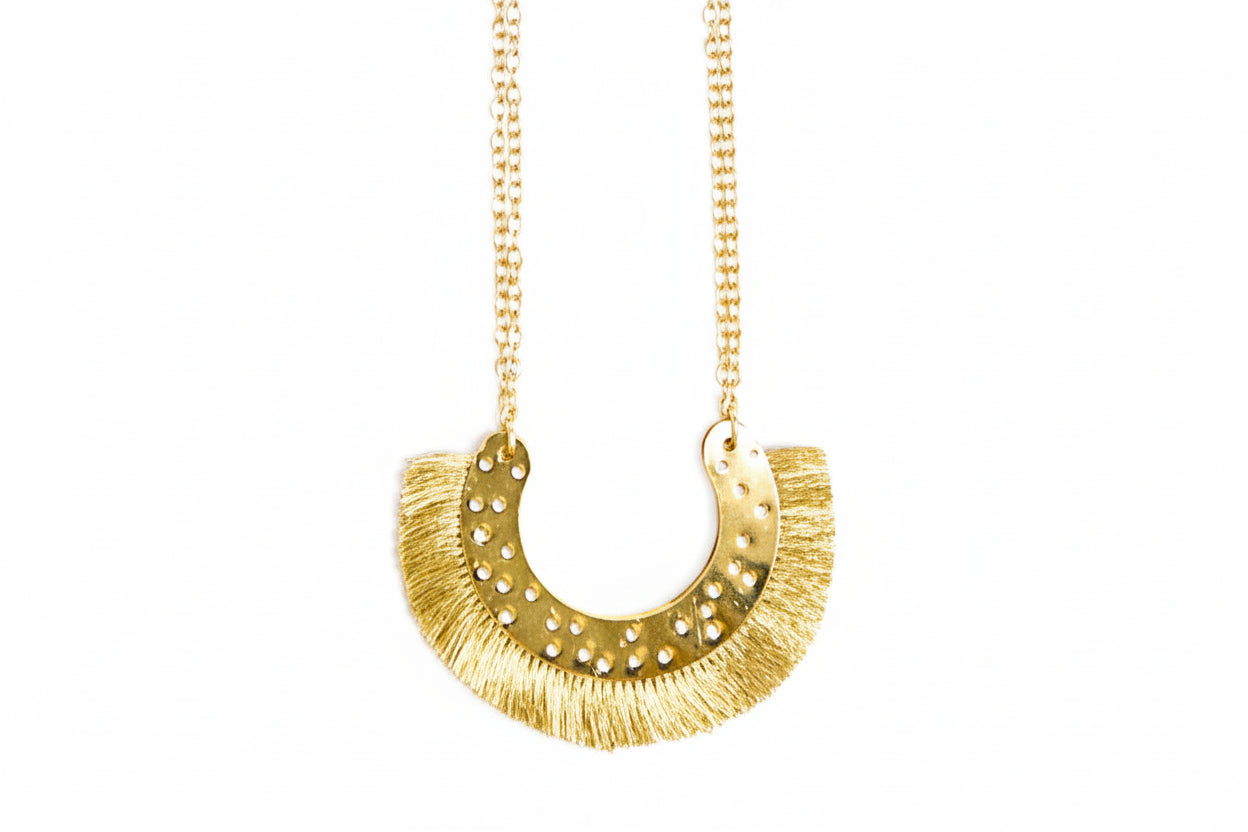 Gold necklace with a fringe pendant on a white background